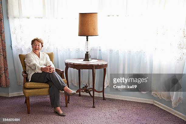senior frau im sessel zu hause - old woman sitting stock-fotos und bilder