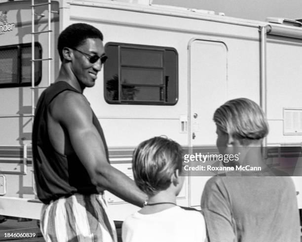 Scottie Pippen of the Chicago Bulls, wearing sunglasses, a tank top and striped shorts greets young fans outside a motor home on the set of a Nike...