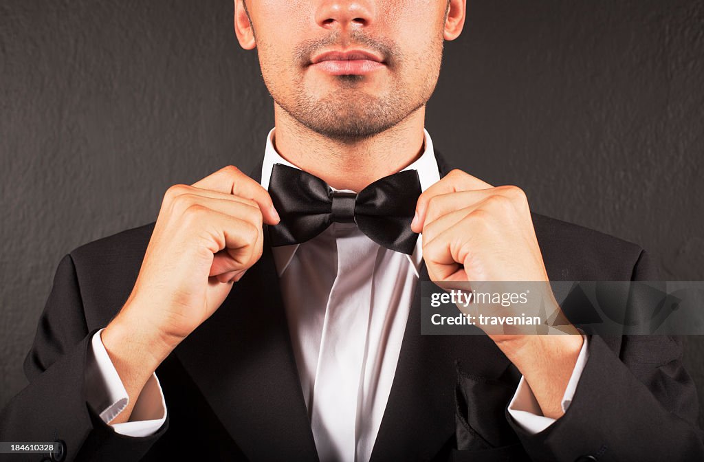 A man in a suit tying his bow tie