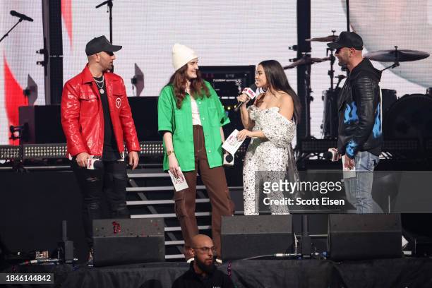 Mikey V , Gianna Gravalese , and Frankie V present a prize to a contest winner onstage during iHeartRadio KISS108's Jingle Ball 2023 at TD Garden on...