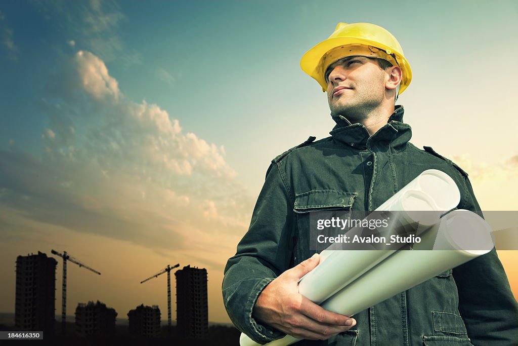 Construction worker on a construction site with blue prints.