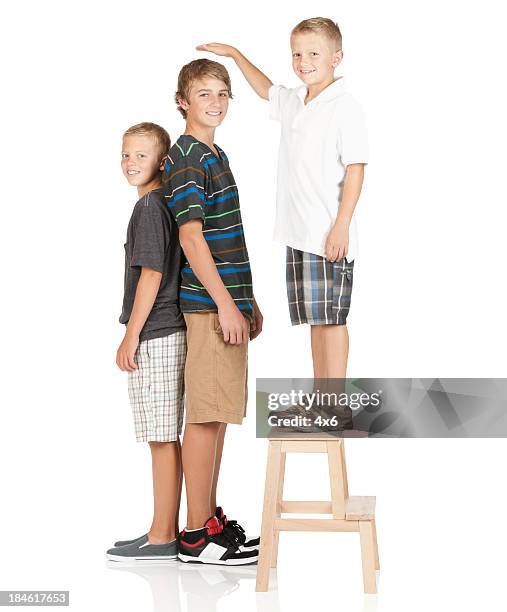 petite garçon debout sur un tabouret et de comparer la hauteur - boys kids compare height photos et images de collection
