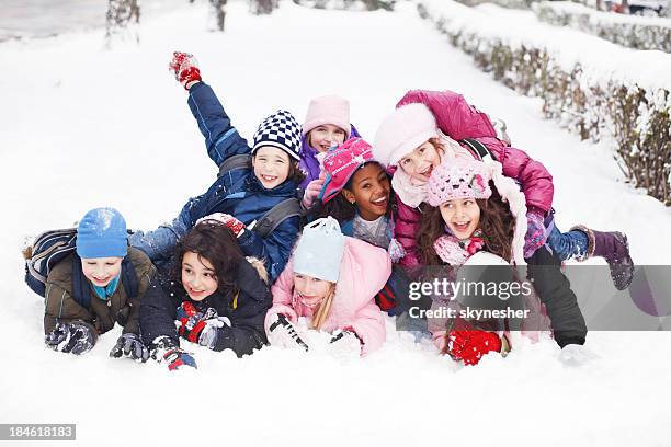 funny group of children are lying in the snow. - snow fun stock pictures, royalty-free photos & images
