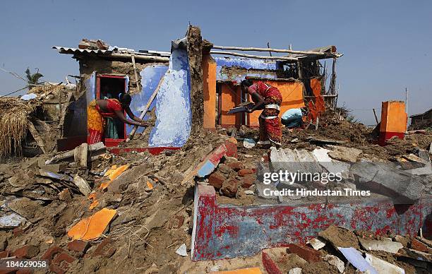 Fishermen family salvage materials from their house damaged during Cyclone Phailin at the fishermen's village in New Podampetta village near Humma on...