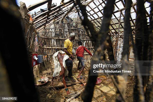 Fishermen family salvage materials from their house damaged during Cyclone Phailin at the fishermen's village in New Podampetta village near Humma on...