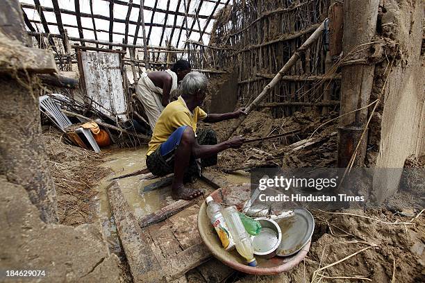 Fishermen family salvage materials from their house damaged during Cyclone Phailin at the fishermen's village in New Podampetta village near Humma on...