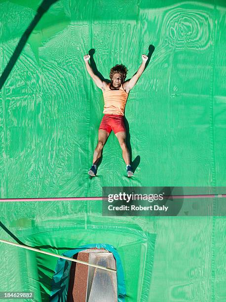 athlete laying and cheering on crash mat after a pole vault - pole vault stock pictures, royalty-free photos & images