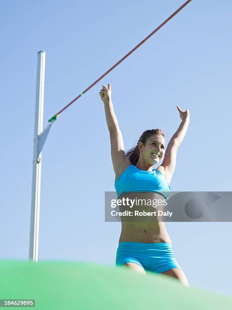 athlete with hand raised after pole vault in an arena - pole vault stock pictures, royalty-free photos & images