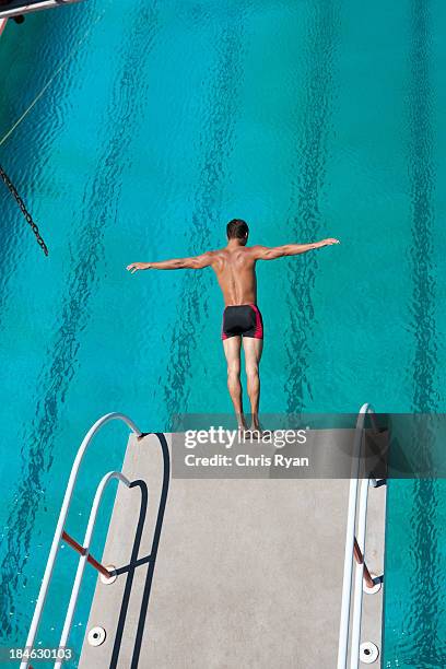 diver midair going into pool - public pool diving board stock pictures, royalty-free photos & images