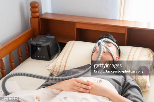 man suffering from obstructive sleep apnea and sleeping with a cpap mask - nose tube stock pictures, royalty-free photos & images