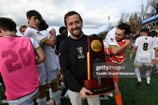 Head coach Justin Oliver of the St. Olaf Oles holds the championship trophy after a win against the Amherst Mammoths during the 2023 Division III...