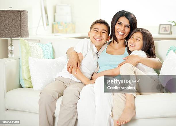 mother and children sitting on a sofa - tweezits bankje stockfoto's en -beelden