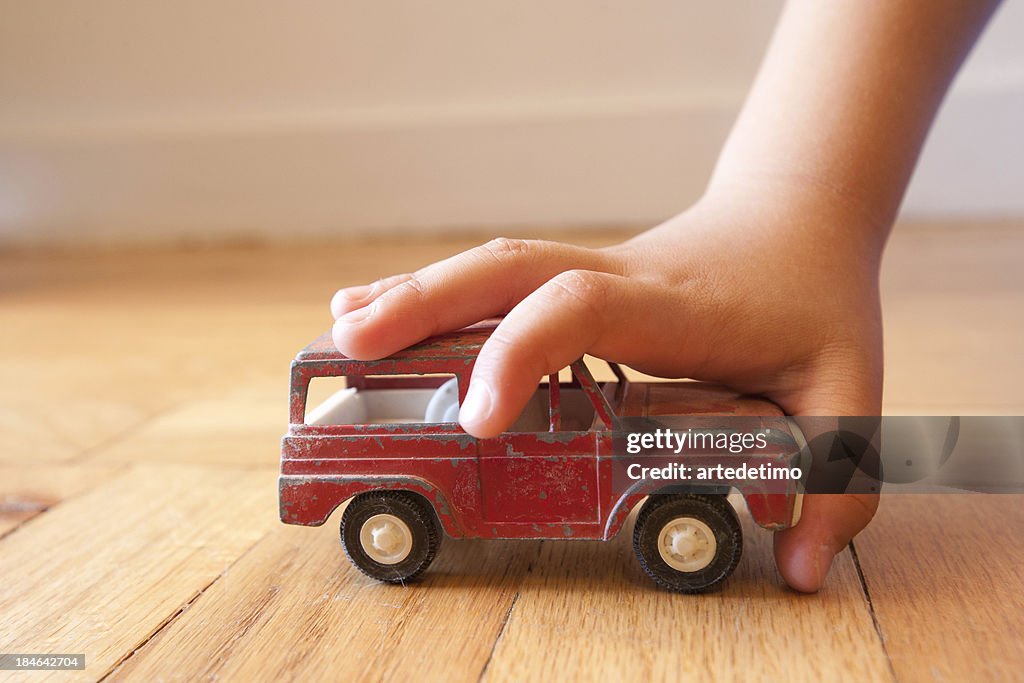 Young boy stopping a toy SUV in its tracks