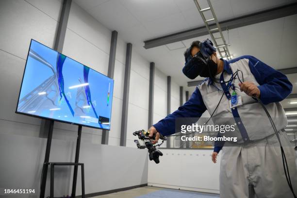 Worker wears a virtual reality headsets as he simulates painting an automobile body inside a training facility at the Subaru Corp. Gunma Yajima Plant...