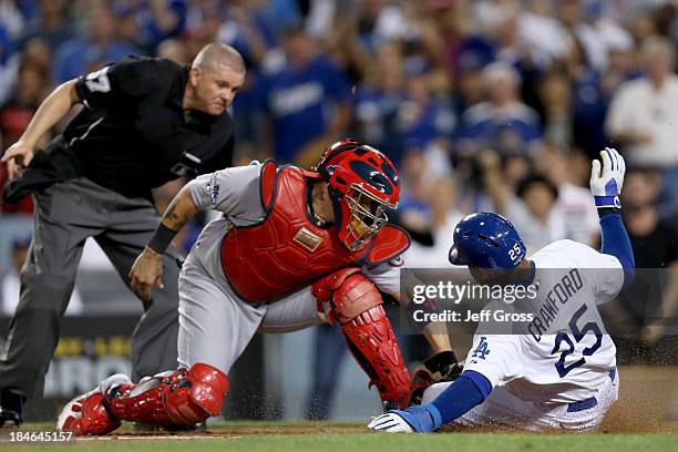 Carl Crawford of the Los Angeles Dodgers slides safely under the tag of Yadier Molina of the St. Louis Cardinals as he scores a run in the eighth...