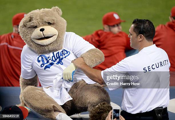 Fan dressed as a bear is escorted out of the stadium for dancing on the St. Louis Cardinals dugout in the eighth inning as the Cardinals take on the...