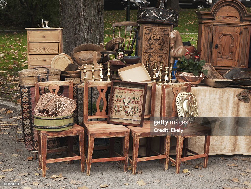 Stand at an outdoor market with antique wooden furniture.