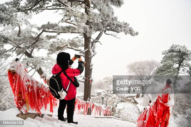 Tourist takes photos of Huashan Mountain covered by snow on December 11, 2023 in Weinan, Shaanxi Province of China. Heavy snow hit northern China on...