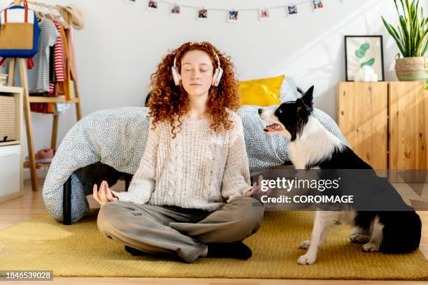 young woman sitting on the floor of her bedroom relaxing with her dog - portrait chantier stock-fotos und bilder