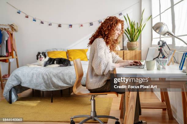 young woman sitting at desk in her bedroom working from home - homeoffice stock-fotos und bilder