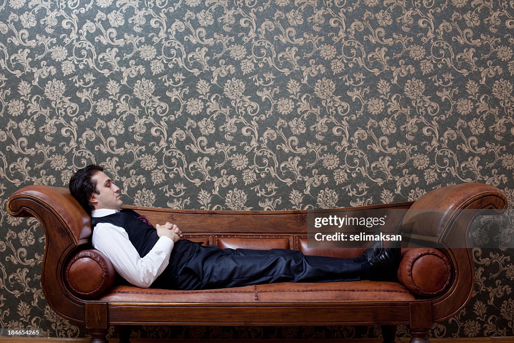 Mesmerized man lying down on coach in psychiatrist office