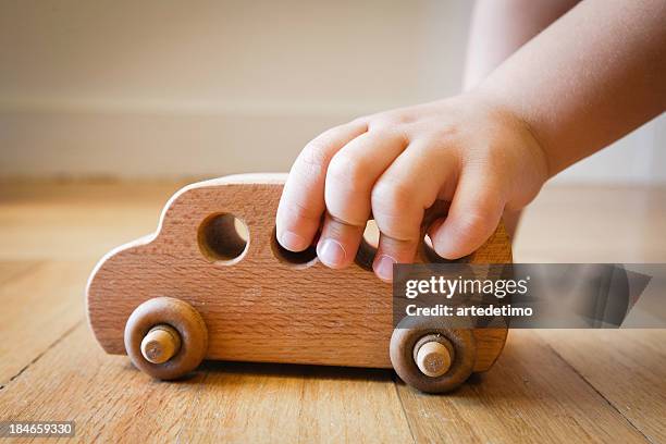 child playing with wooden toy bus on wooden floor - eternal youth stock pictures, royalty-free photos & images