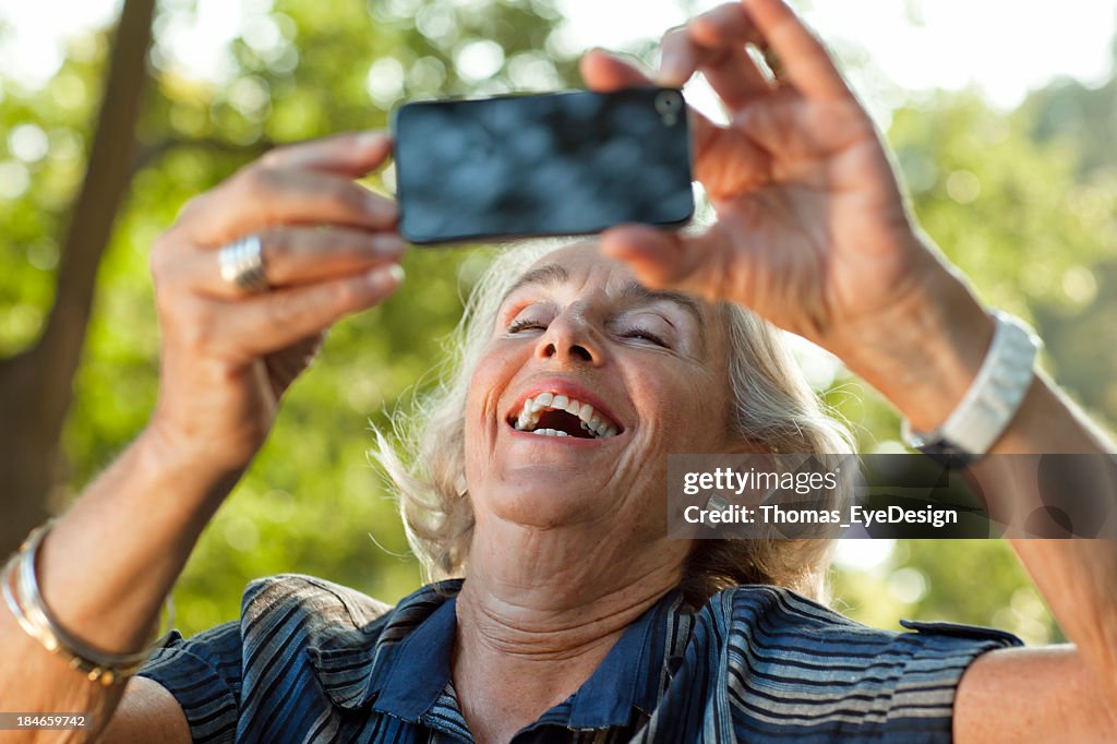 Guapo Senior mujer tomando fotos con el teléfono inteligente