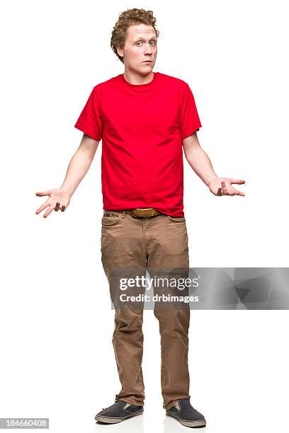 shrugging young man - rode broek stockfoto's en -beelden