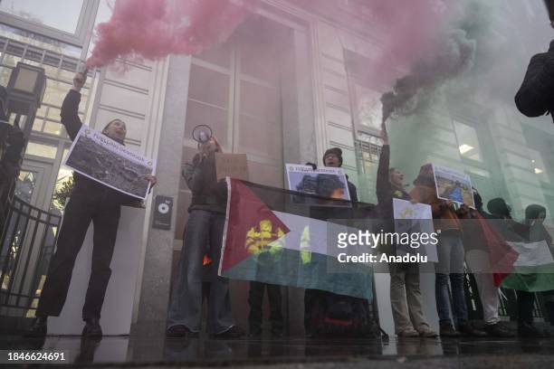 Group of people gather in front of the entrance of the company headquarters holding a banner and Palestinian flag as they protest The British...