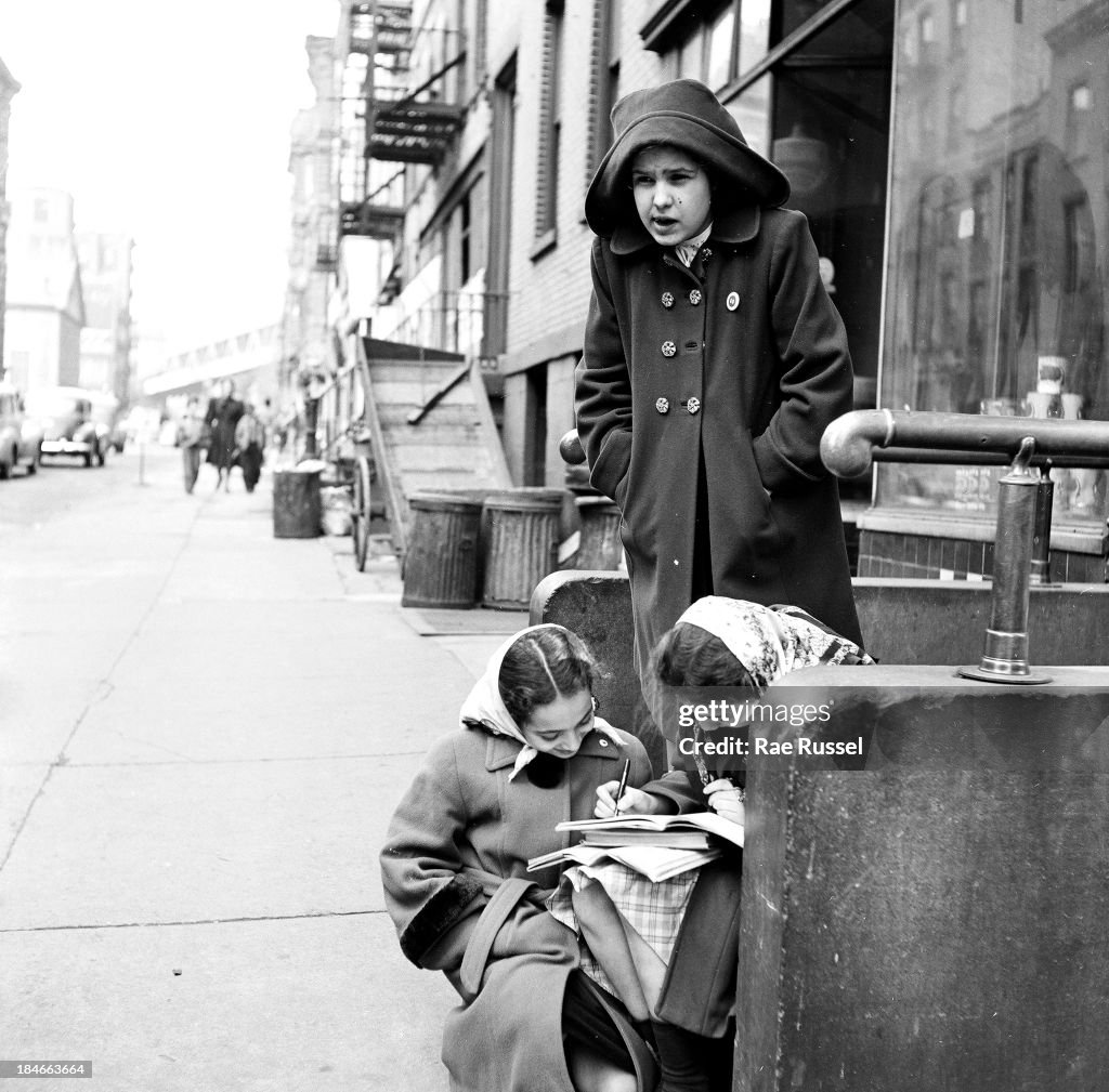 Child Stooping View of a trio of young girls on a stoop as they look at their school ...