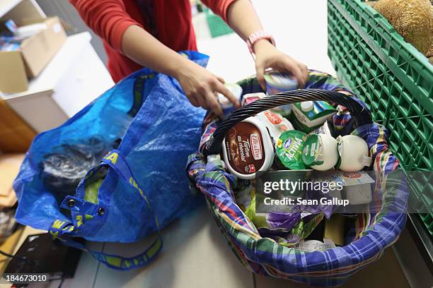 Volunteer places gorceries in a basket for a mother of four at the Falkenseer Tafel food bank on October 15, 2013 in Falkensee, Germany. The...