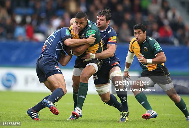 Luther Burrell of Northampton is tackled by Remi Lamerat and Rodrigo Capo Ortega during the Heineken Cup match between Castres and Northampton Saints...
