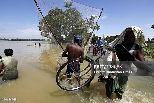 People cross a road under flood waters at village Sunderhata after the cyclone Phailin on October 15, 2013 about 20 kilometers north of Balasore,...
