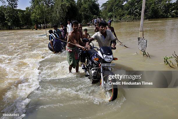 People cross a road under flood waters at village Sunderhata after the cyclone Phailin on October 15, 2013 about 20 kilometers north of Balasore,...