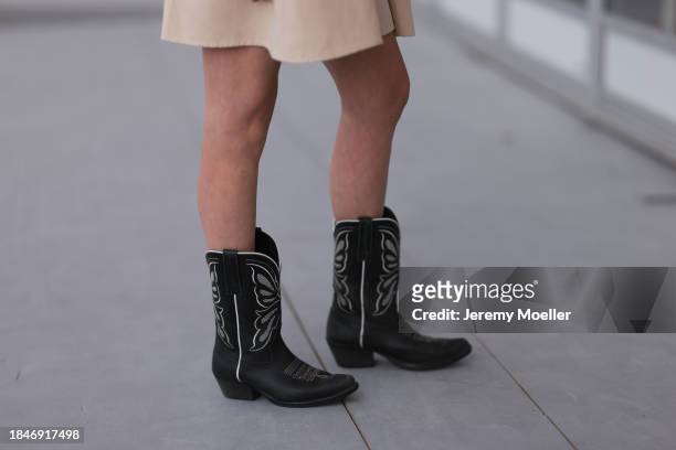Isabella Gosen seen wearing beige linen belted short dress with puff sleeves and black leather cowboy boots, on December 10, 2023 in Miami, Florida.