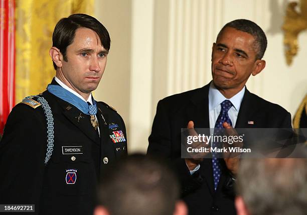 President Barack Obama applauds former U.S. Army Captain William Swenson after giving him the Medal of Honor during a ceremony in the East Room of...
