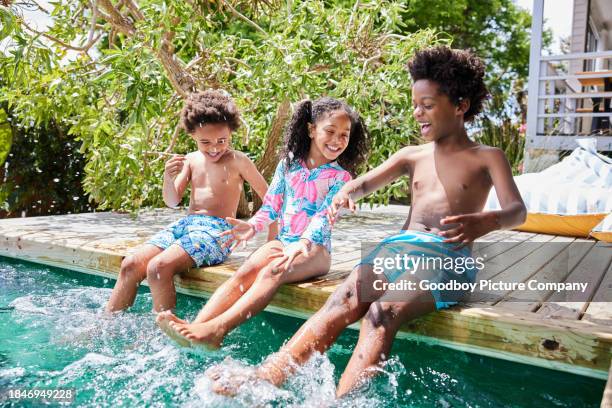 laughing children splashing in their swimming pool at home in summer - boy-with-a-girl-playing-at-the-poolside stock pictures, royalty-free photos & images