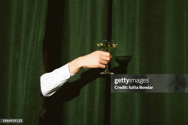 hand with a martini glass - dark green curtains photos et images de collection