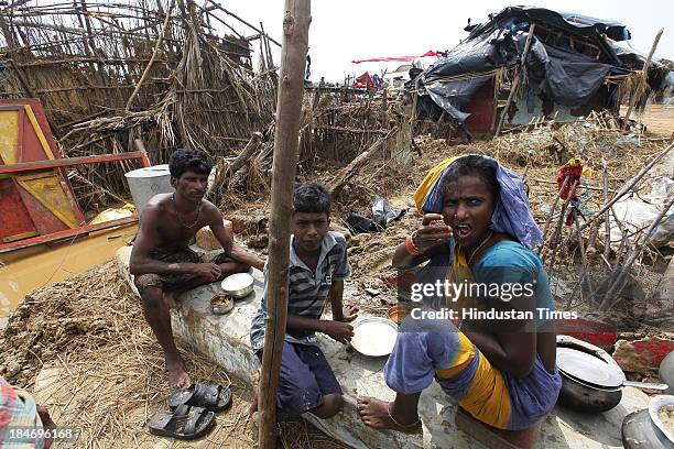 Indian fishermen family eating rice and fish near their damaged houses after cyclone Phailin in Podampetta village on October 15, 2013 about 190...