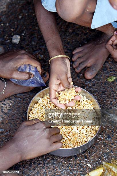 Family marooned by flood waters eats puffed rice on NH5 after Cyclone Phailin at a temporary relief camp on October 15, 2013 in Balasore, India....