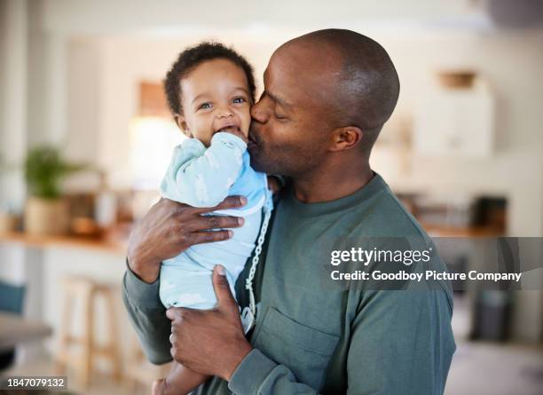 loving dad kissing his baby boy on the cheek at home - father baby stock pictures, royalty-free photos & images