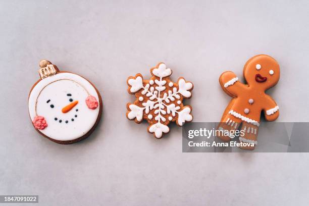 christmas gingerbread cookies in different shapes: a snowflake, a gingerbread man and a snowman with a cute smiling face. christmas symbols. christmas and new year celebration concept. frame with copy space. - glassa foto e immagini stock