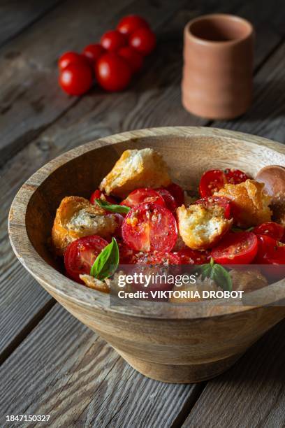 rustic salad of fresh cherry tomatoes, croutons, basil and aromatic olive oil in wooden bowl on old wooden background. lassic italian dish, panzanella appetizer. - bread salad stock pictures, royalty-free photos & images