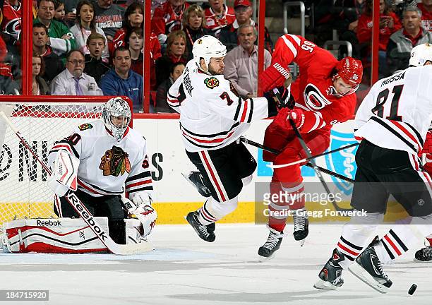 Ron Hainsey of the Carolina Hurricanes collides with Brent Seabrook of the Chicago Blackhawks in front of goaltender Corey Crawford during their NHL...