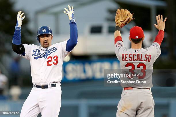 Adrian Gonzalez of the Los Angeles Dodgers reacts after hitting a double in the fourth inning alongside Daniel Descalso of the St. Louis Cardinals in...