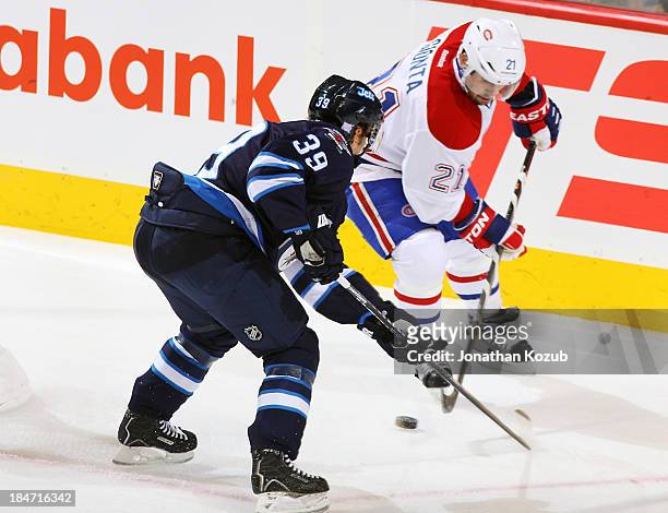 Tobias Enstrom of the Winnipeg Jets and Brian Gionta of the Montreal Canadiens battle for the loose puck during first period action at the MTS Centre...