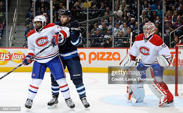 Goaltender Carey Price of the Montreal Canadiens looks around a screen set by teammate P.K. Subban and Andrew Ladd of the Winnipeg Jets during first...