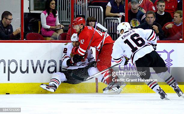 Brett Sutter of the Carolina Hurricanes lands a hard check on Michal Rozsival of the Chicago Blackhawks during play at PNC Arena on October 15, 2013...