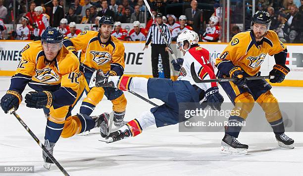 Jonathan Huberdeau of the Florida Panthers is upended by Mattias Ekholm and Kevin Klein of the Nashville Predators at Bridgestone Arena on October...