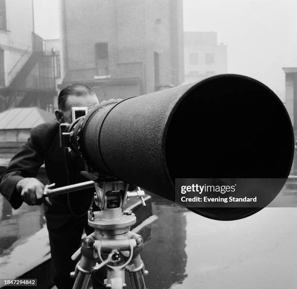 An Evening Standard photographer using a camera with a long telephoto lens, London, September 26th 1957.